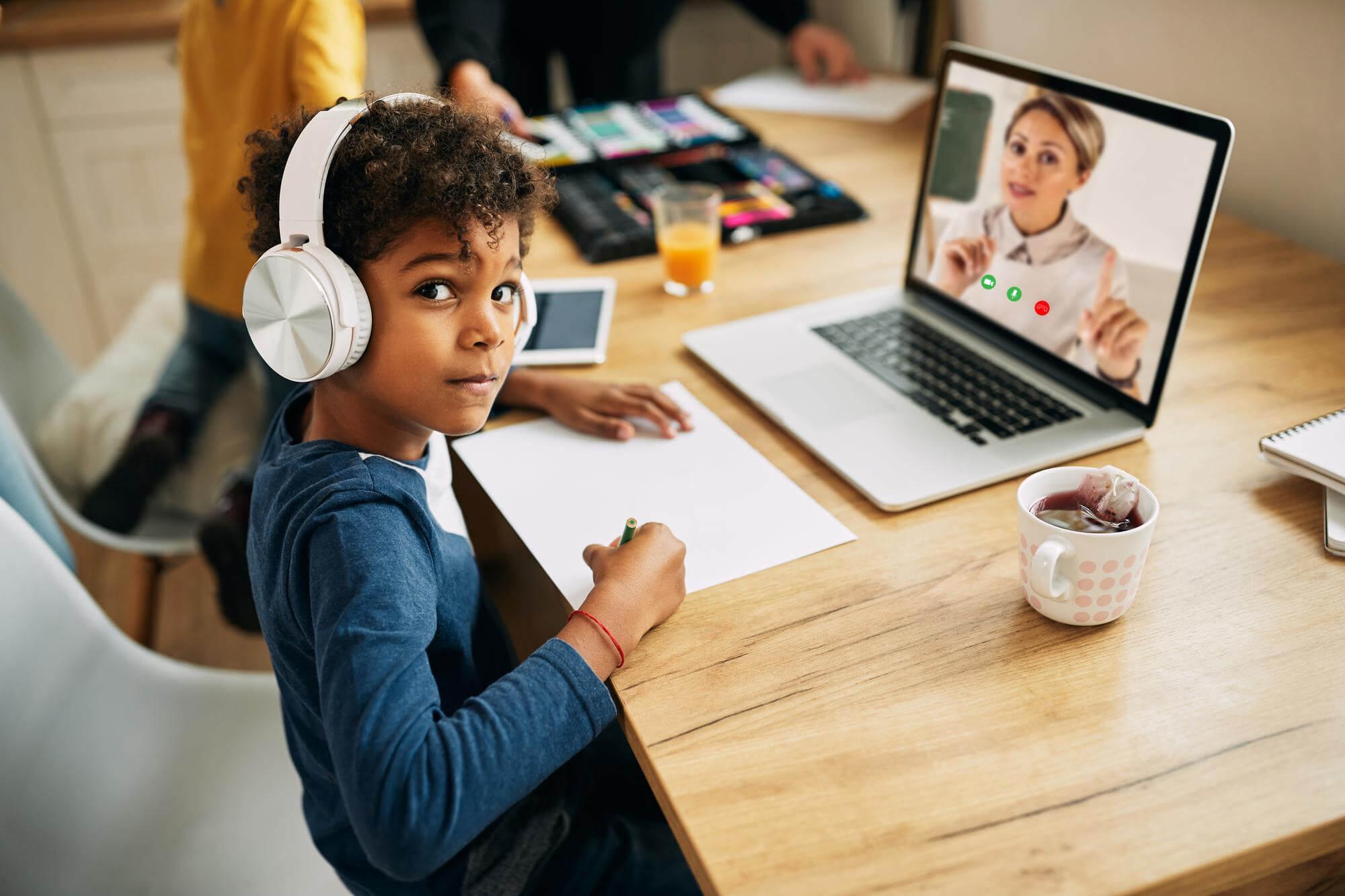 african american boy with headphones following online class laptop from home 1
